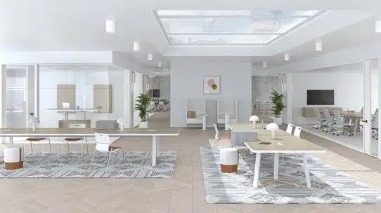 Grand espace de bureaux communs lumineux, deux tables longues modernes avec fini en bois clair sont au centre. À l'arrière, il y a des bureaux fermés simples avec des murs vitrés