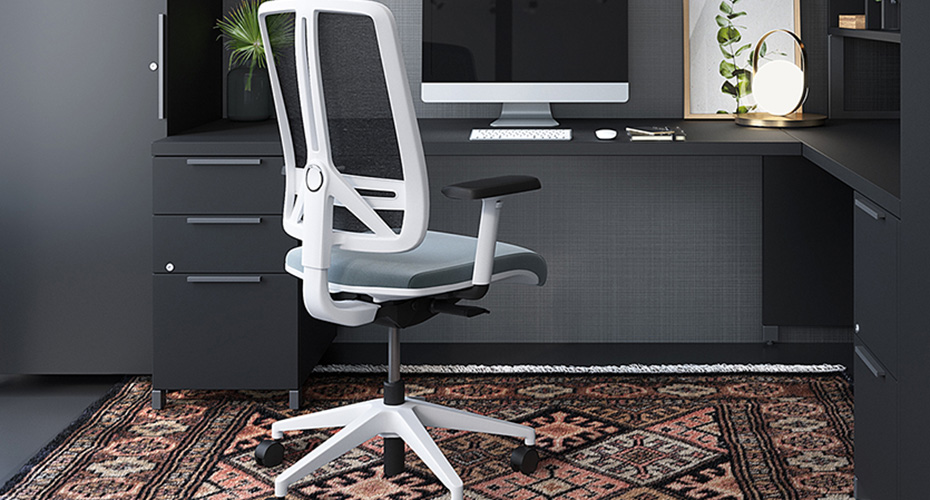 Chaise ergonomique de bureau blanche sur roulettes. Dessous, il y a un tapis marocain, et autour il y a un bureau en bois noir moderne.