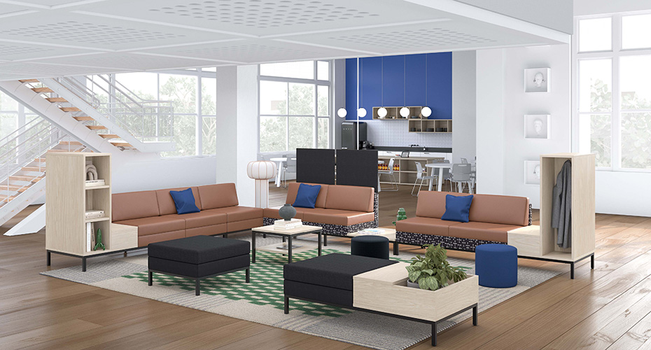 Espace lumineux avec cuisiniette à l'arrière et espace de salon au centre. Fauteuils modulables en cuir posés sur un tapis quadrillé vert et beige.