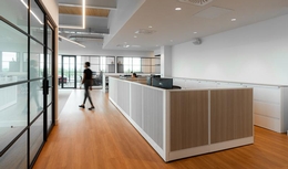 Espace ouvert avec cubicule et mobilier de bureau moderne. Plancher de bois franc, mur vitré.