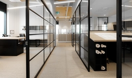 Couloir dans un bureau, deux murs vitrés donnant accès sur des espaces bureaux modernes et éclairés